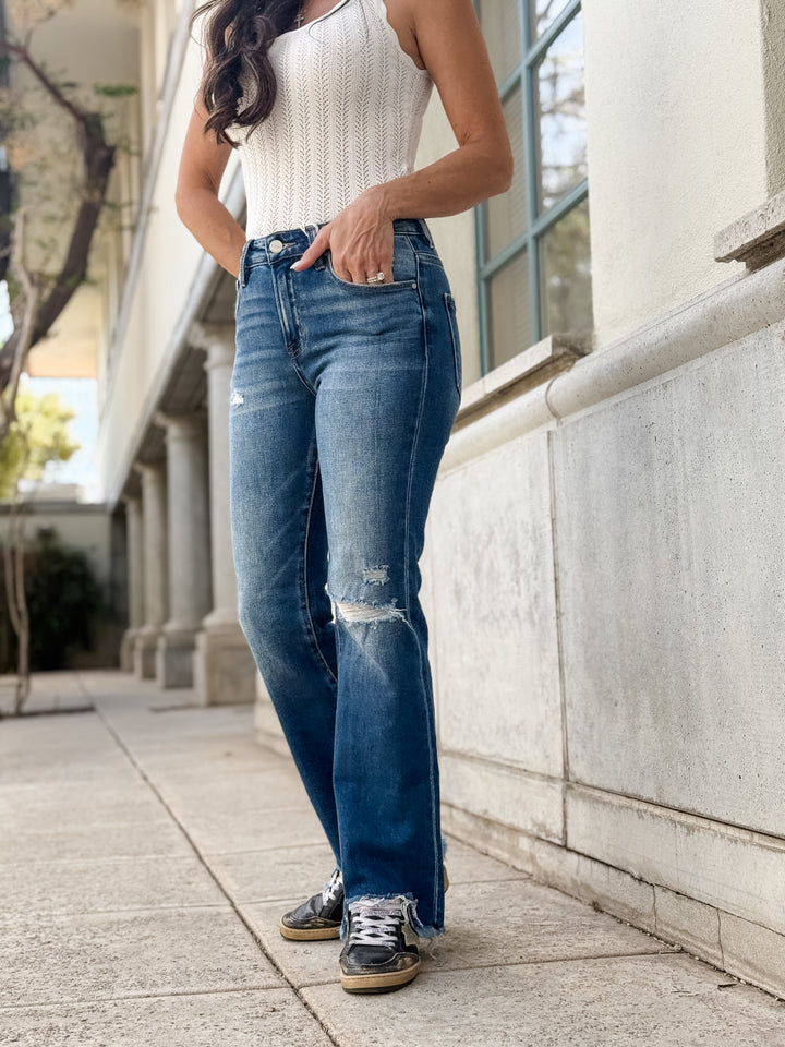 Straight-leg denim, ripped knee, raw hem.