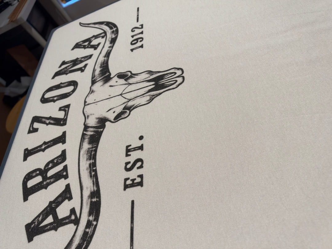 Arizona Est. 1912 graphic with distressed lettering and a longhorn skull on a light-colored tee